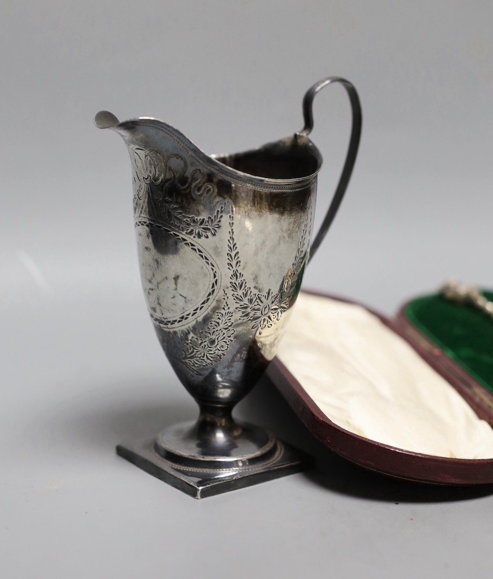 A George III silver helmet shaped cream jug, London, 1791, 13.2cm(a.f.), a silver menu holder and a cased silver sifter spoon.